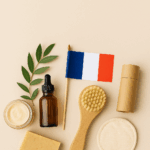 Produits cosmétiques français durables Fleurs de Café, flacon en verre, brosse en bois et feuille verte sur fond clair.